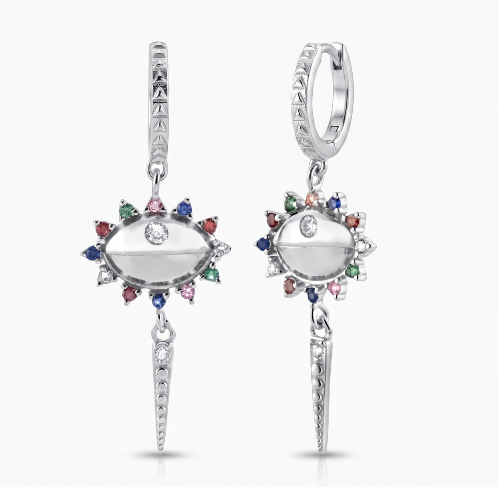 A pair of silver huggie hoop drop earrings featuring an eye-shaped centerpiece with a clear center stone, surrounded by a halo of small multicolored gemstones (red, green, blue, pink, orange) and a dangling spear-shaped charm at the bottom.