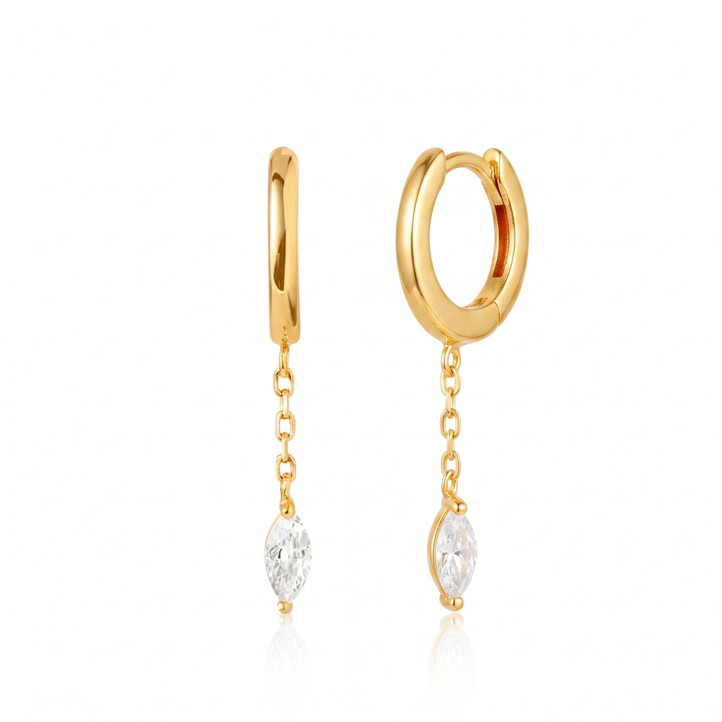 A pair of gold huggie hoop earrings with dangling chain links and marquise-cut clear gemstones, shown on a clean white background with a soft reflection.