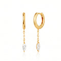 A pair of gold huggie hoop earrings with dangling chain links and marquise-cut clear gemstones, shown on a clean white background with a soft reflection.