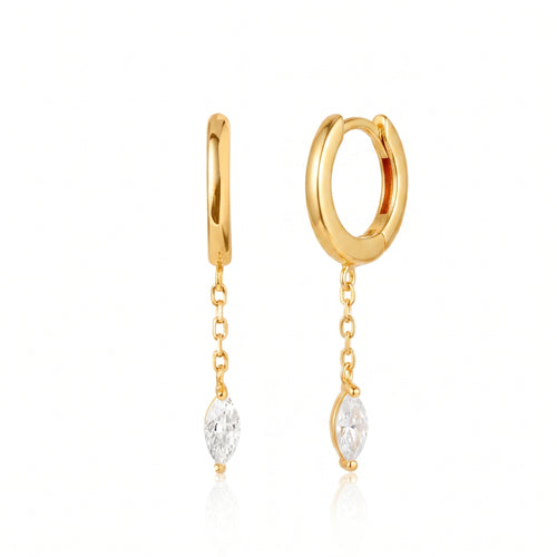 A pair of gold huggie hoop earrings with dangling chain links and marquise-cut clear gemstones, shown on a clean white background with a soft reflection.
