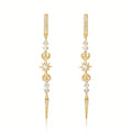 A pair of gold dangle earrings with clear gemstones forming celestial motifs including stars, crescent moons, and a vertical bar at the top, displayed on a clean white background.