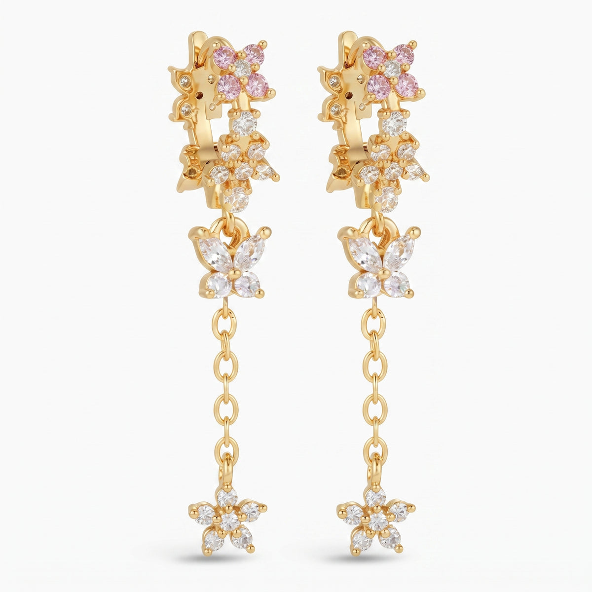 A pair of gold dangle earrings featuring butterfly and flower motifs, embellished with clear cubic zirconia stones and pink gemstones, set against a plain white background.